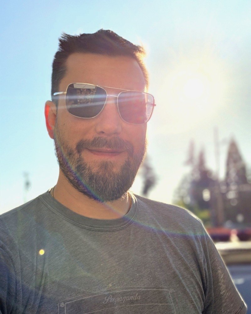 Andrew Dall, co-founder of Emaration, outdoors in sunglasses on a bright afternoon.