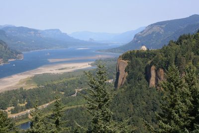 A wide Oregon beach curving toward a forested coastal headland under soft light.